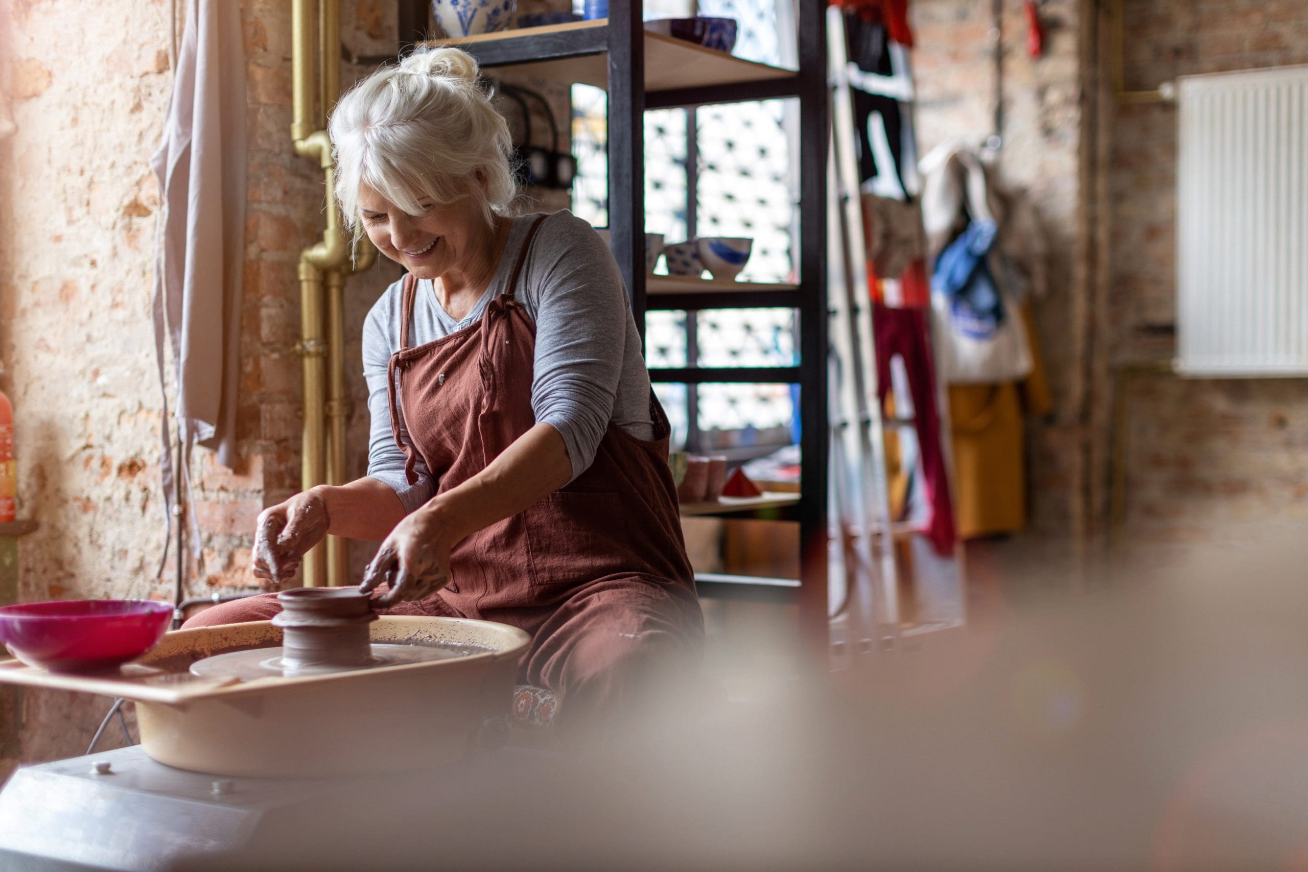Hand made ceramics are formed by a mature woman on a potters wheel