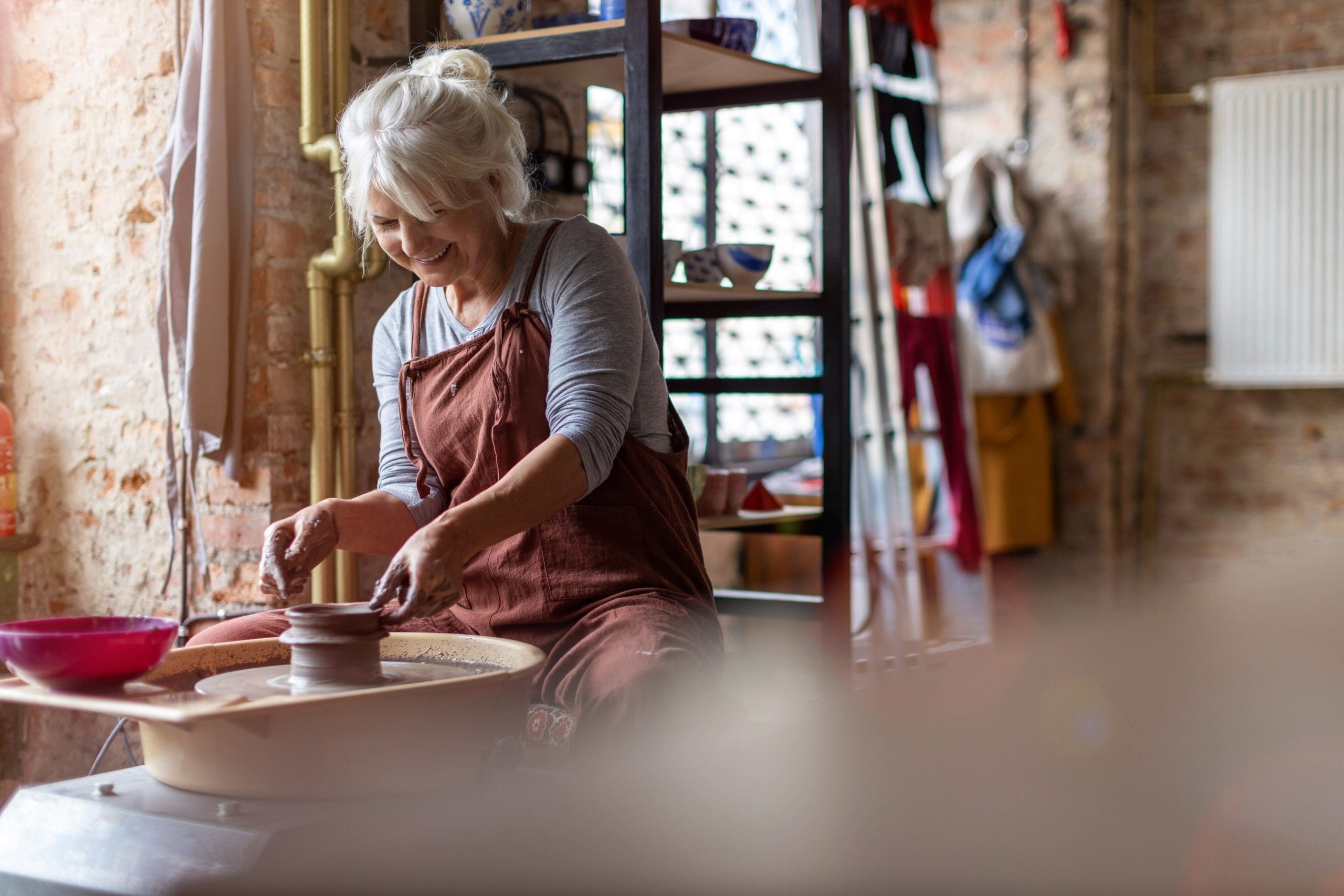 Elderly woman making ceramic work with potter's wheel Hand made ceramics are formed by a mature woman on a potters wheel