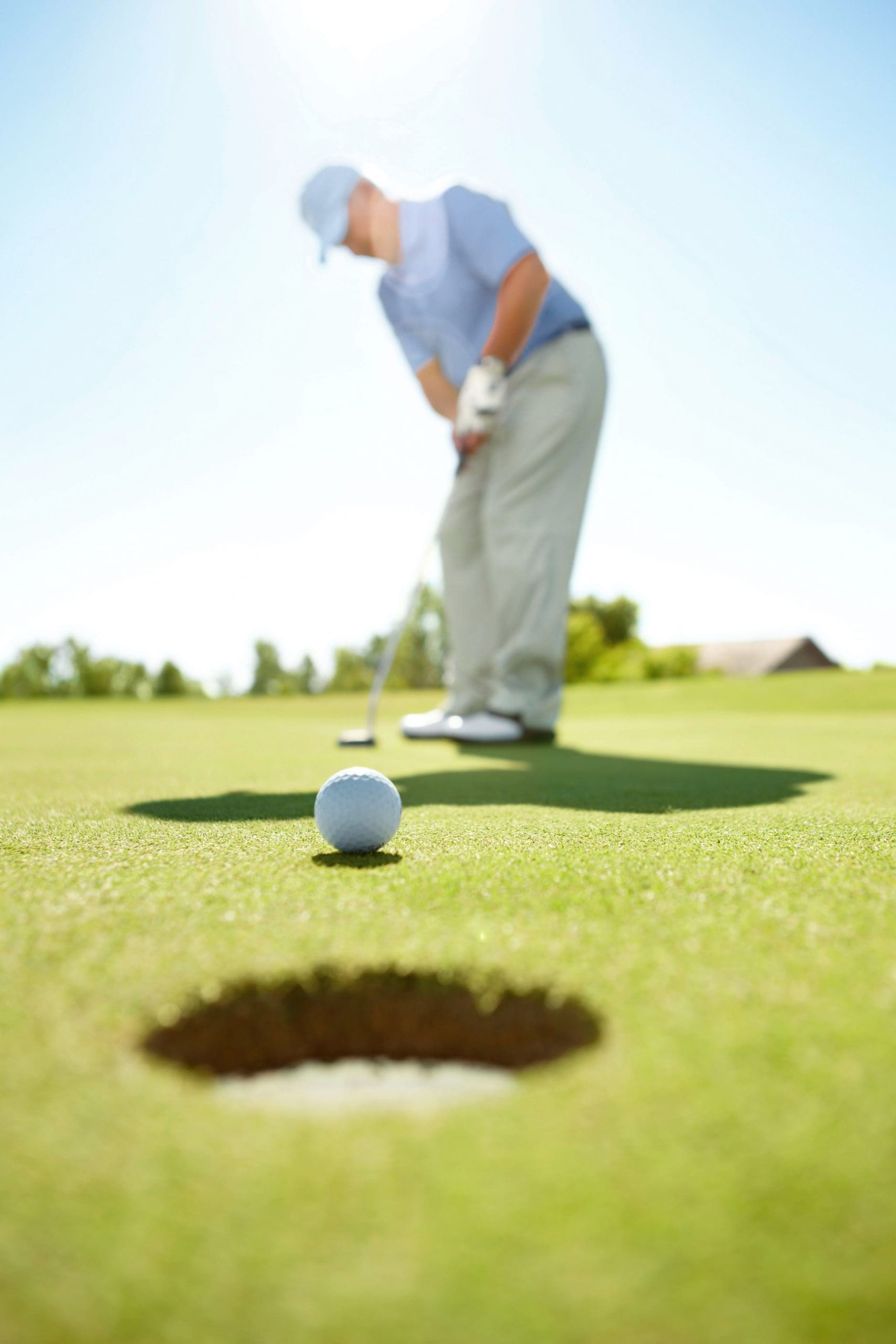 A senior golfer watches his golf ball head for the hole on the putting green