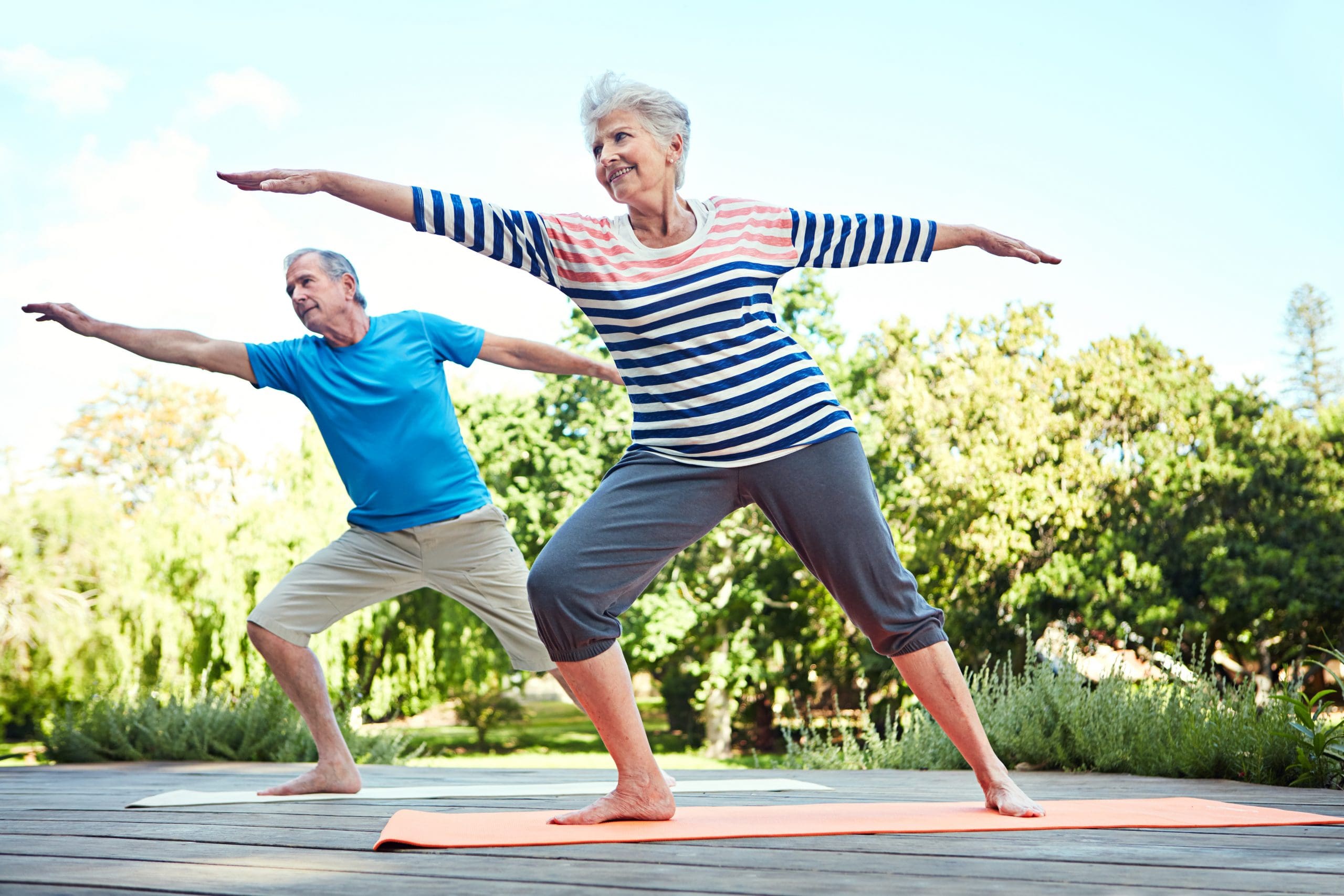 Shot of a senior couple doing yoga together outdoors at Quartet Senior Living