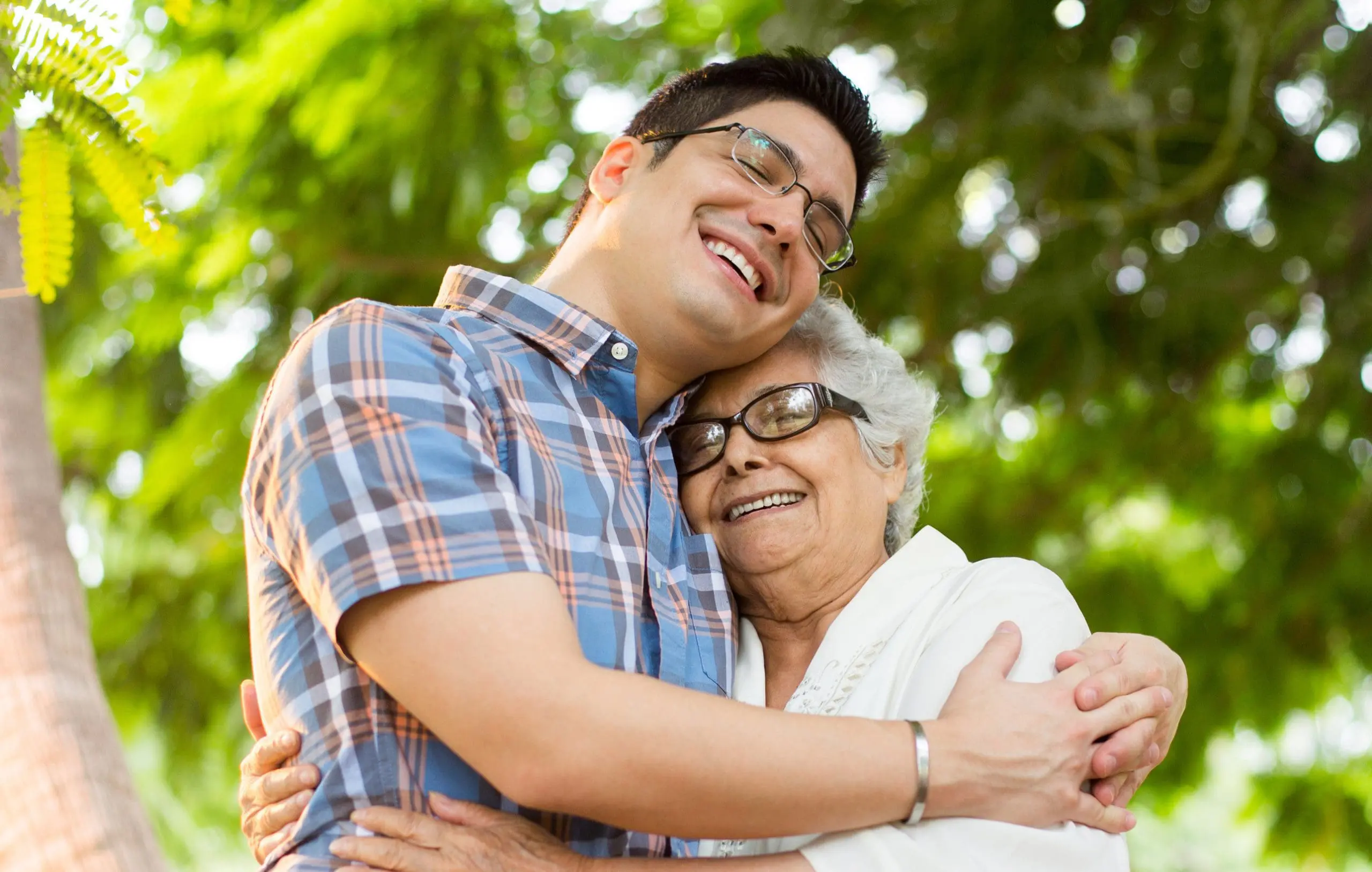 Senior woman and grandson embracing with eyes closed A latin senior woman and her grandson embracing and smiling with eyes closed in a vertical medium shot outdoor