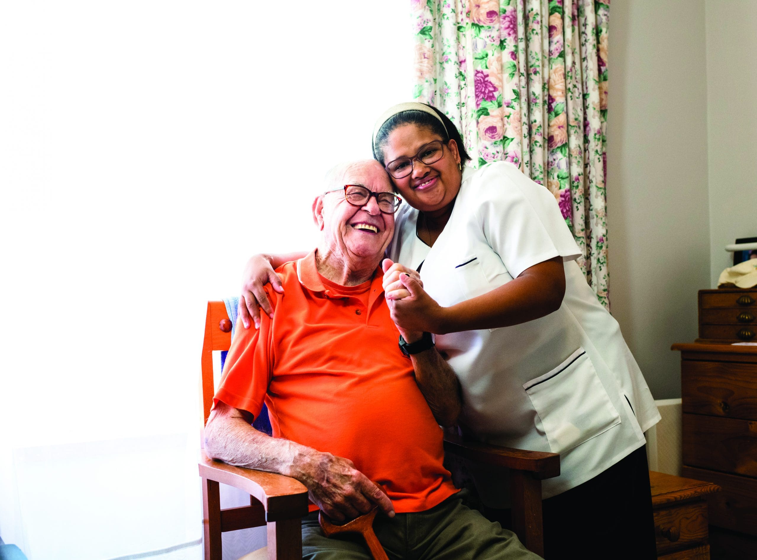 Portrait photo of a smiling senior man and nurse embracing at Quartet Senior Living in Bettendorf Iowa.