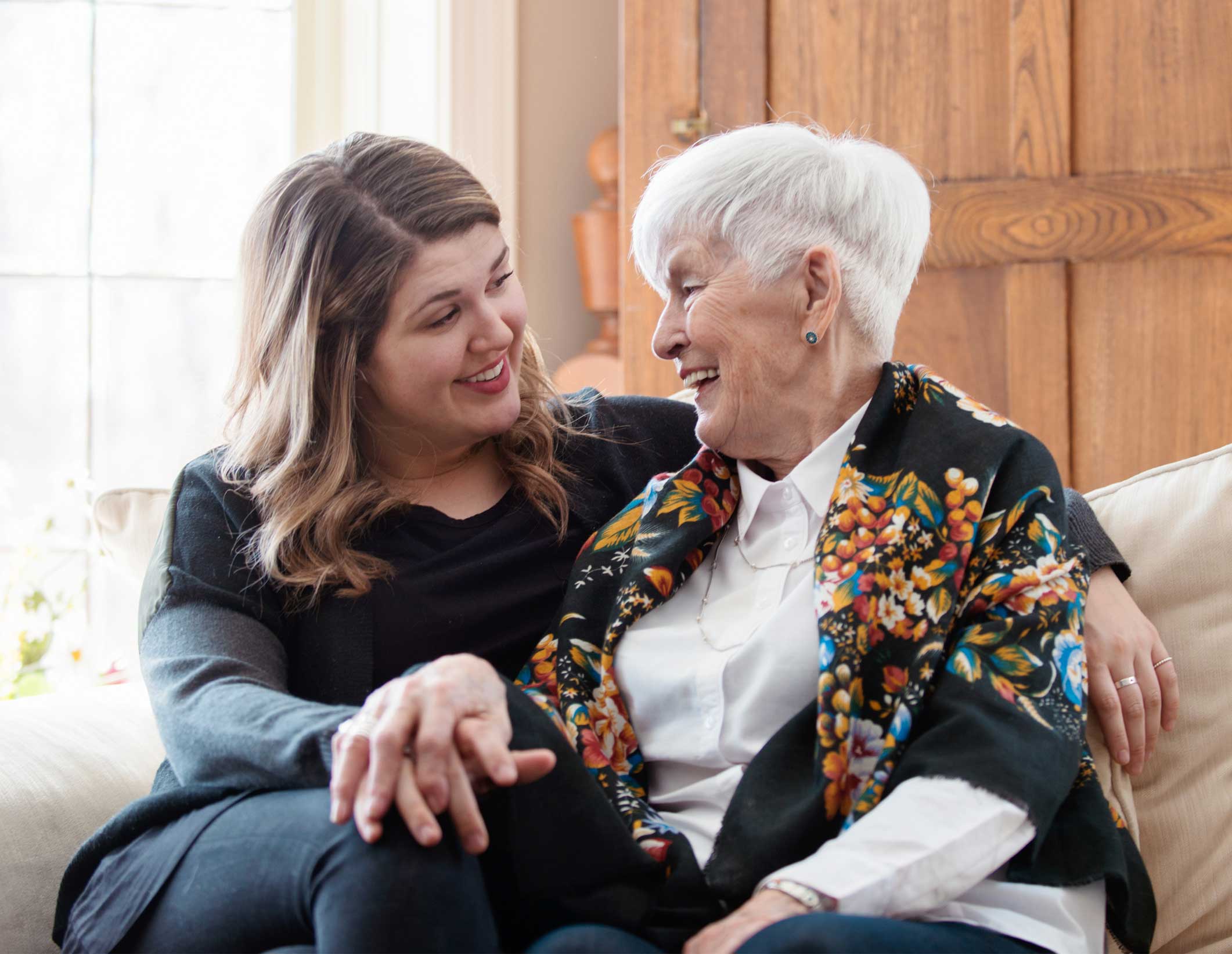 Two ladies sitting on a sofa talking at Quartet Senior Living.