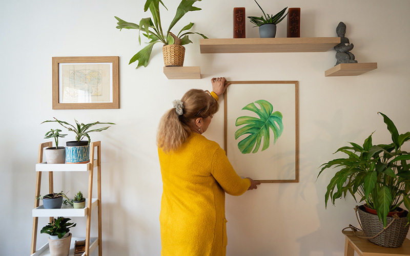 woman hanging art in her senior living apartment