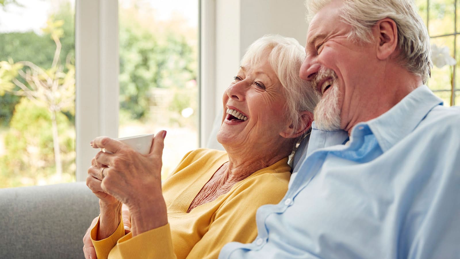 Senior couple sitting together on a couch and laughing