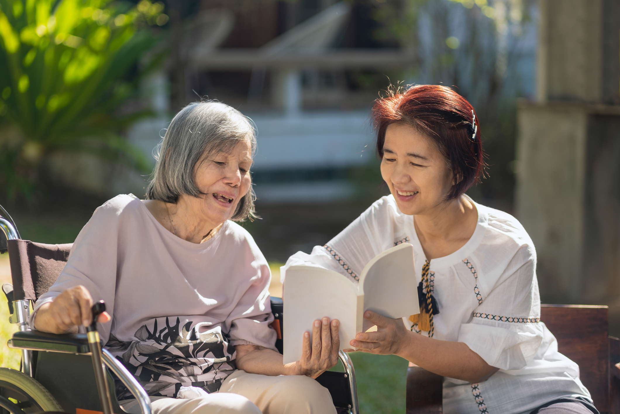 memory care resident reading with her caregiver at Quartet Senior Living