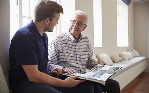 senior man and son looking as a photo album together