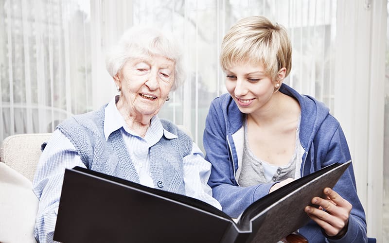 Senior woman and her adult daughter looking through a photo album