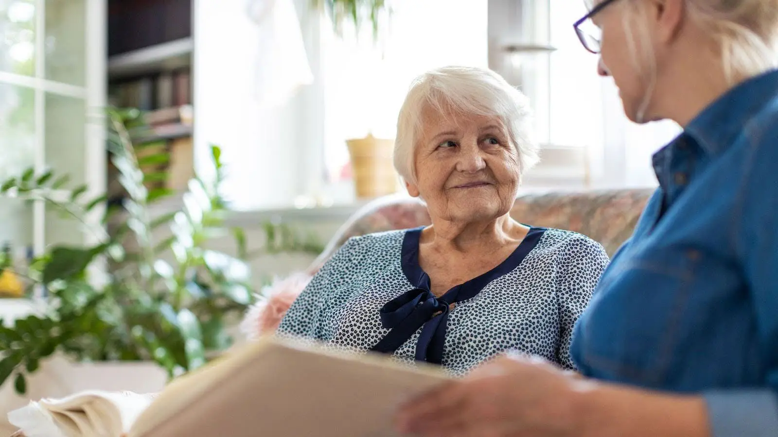 Senior woman reading a book with her caregiver