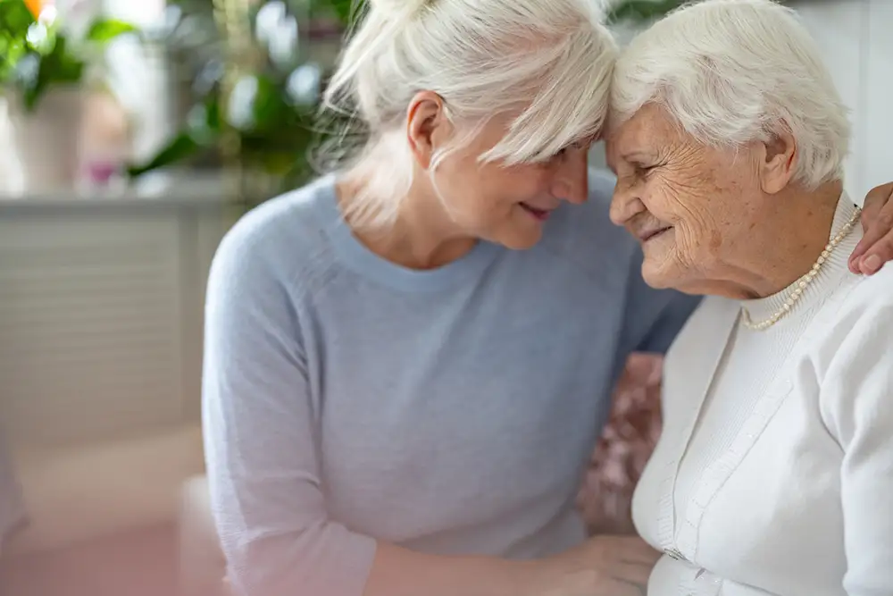 Adult daughter comforting her elderly mother in a supportive moment at Quartet Senior Living in Bettendorf, IA