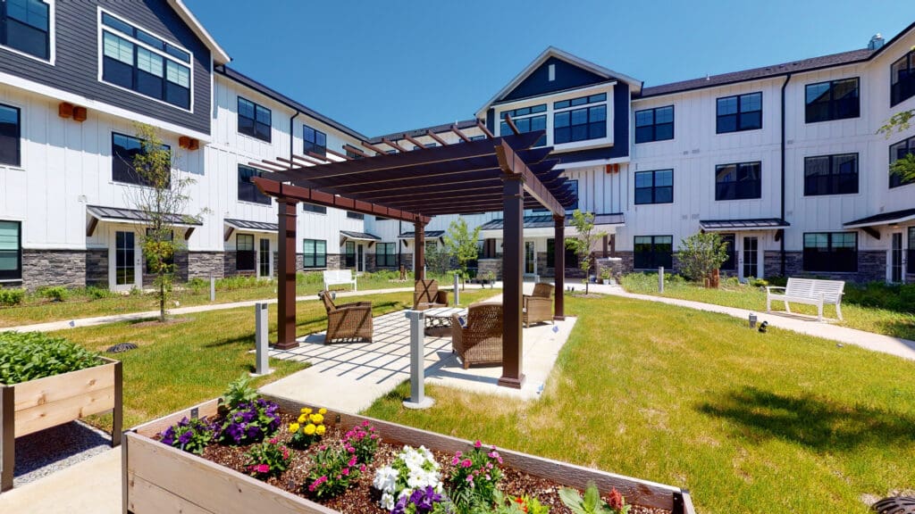 Quarter Senior Living outdoor space with pergola, chairs, raised garden beds