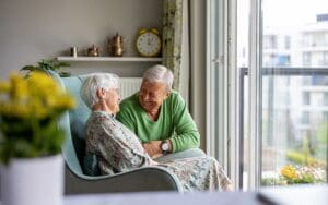 Senior couple smiling and relaxing together on a sunny balcony at Quartet Senior Living in Bettendorf, Iowa