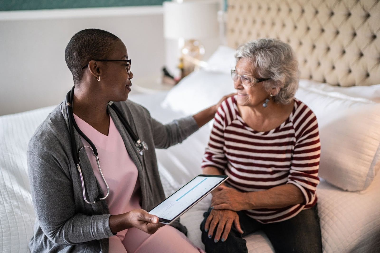Female nurse with tablet consulting with senior woman during in-home healthcare visit in Bettendorf, IA