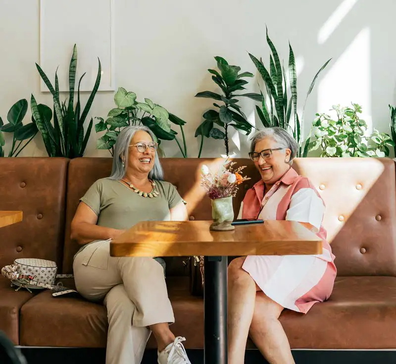 senior-women-laughing-lounge-quartet.jpg Two senior women sharing a laugh in a sunlit lounge area showing Independent Living at Quartet Senior Living in Bettendorf, IA.